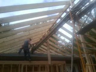 Rafters going up over a new addition with a worker on the wall in Humptulips