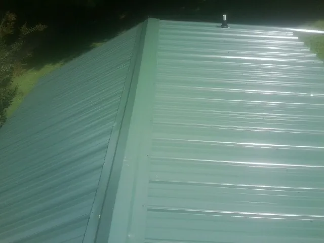 New green metal panels meeting at the ridge of a roof — Flat Roof Repair work by our crew in Humptulips