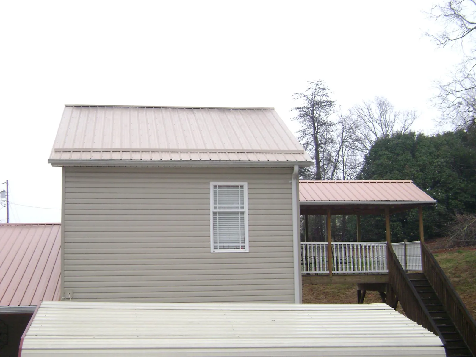 Tan metal roofs on a two story addition and attached porch, from a Roof Replacement job in Humptulips