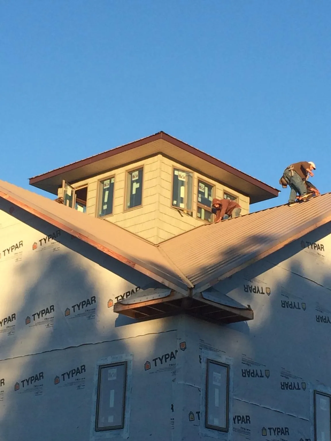 Roofers working around a rooftop cupola on a new metal roof at sunset — Roof Waterproofing in Humptulips by Roofing Brothers